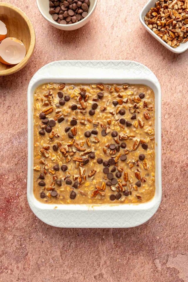 Topping oatmeal with chopped pecans and chocolate chips.