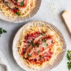 baked chicken parmesan served over pasta and garnished with fresh parsley