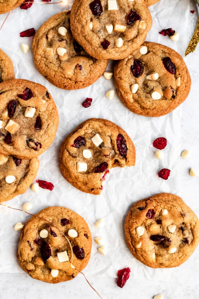 white chocolate cranberry cookies on a white counter and one with a bite taken out