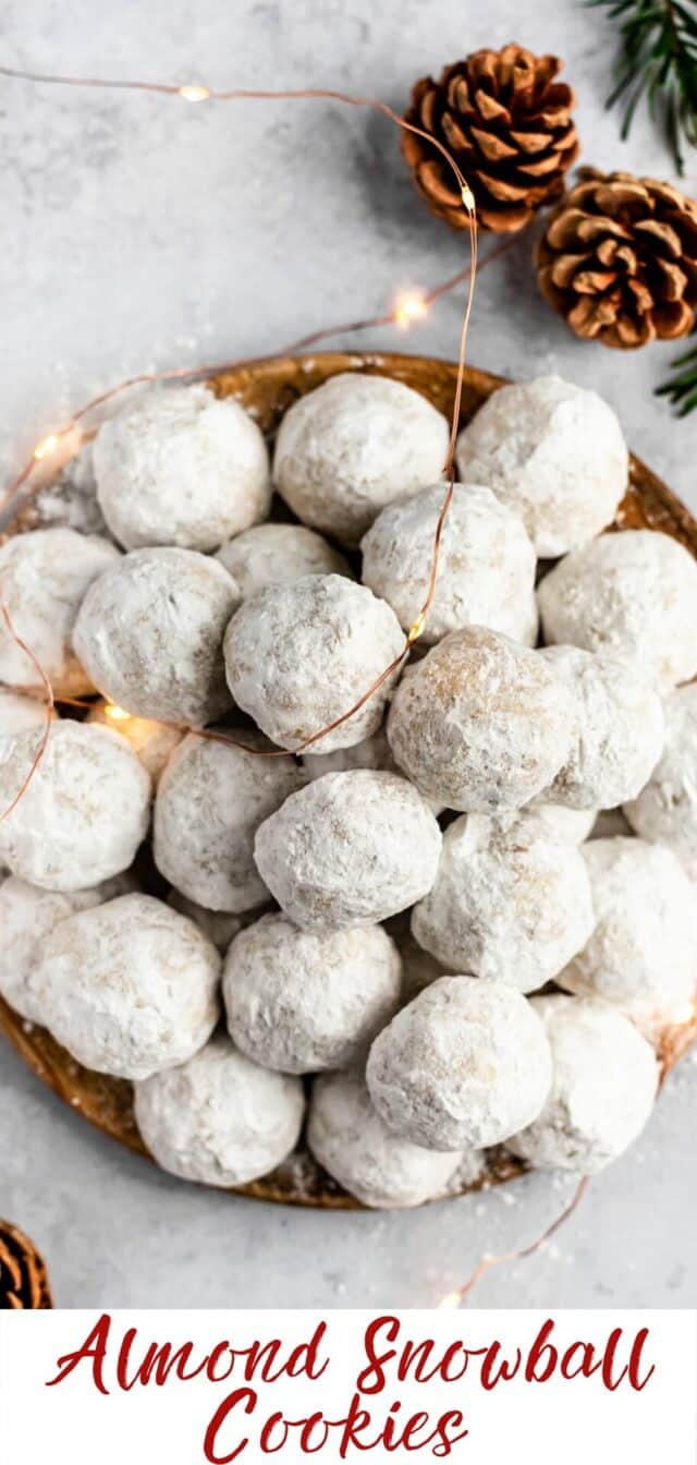a plate filled with almond snowball cookies and Christmas lights