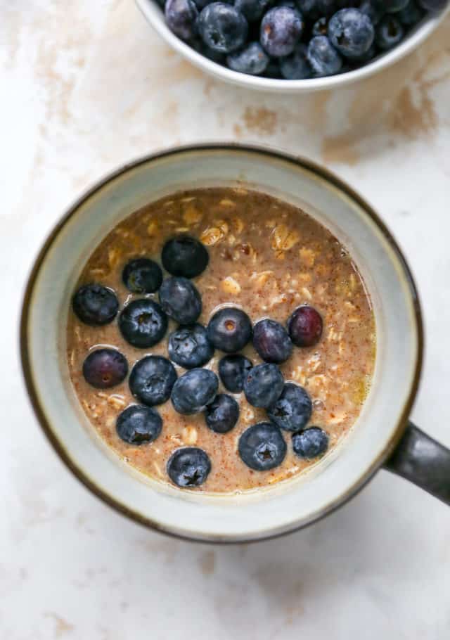 adding blueberries to the top of oatmeal