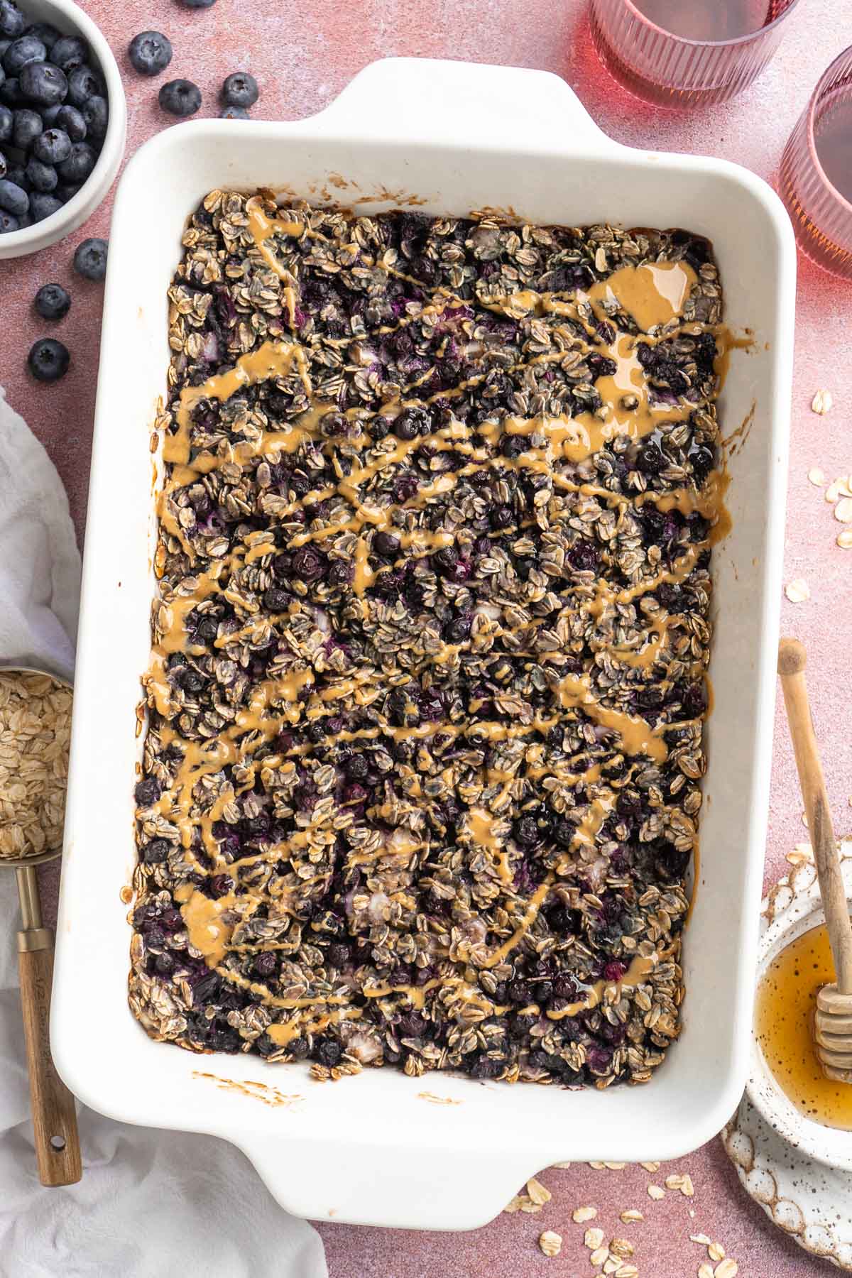 Baked blueberry oatmeal topped with a drizzle of nut butter in a white dish.