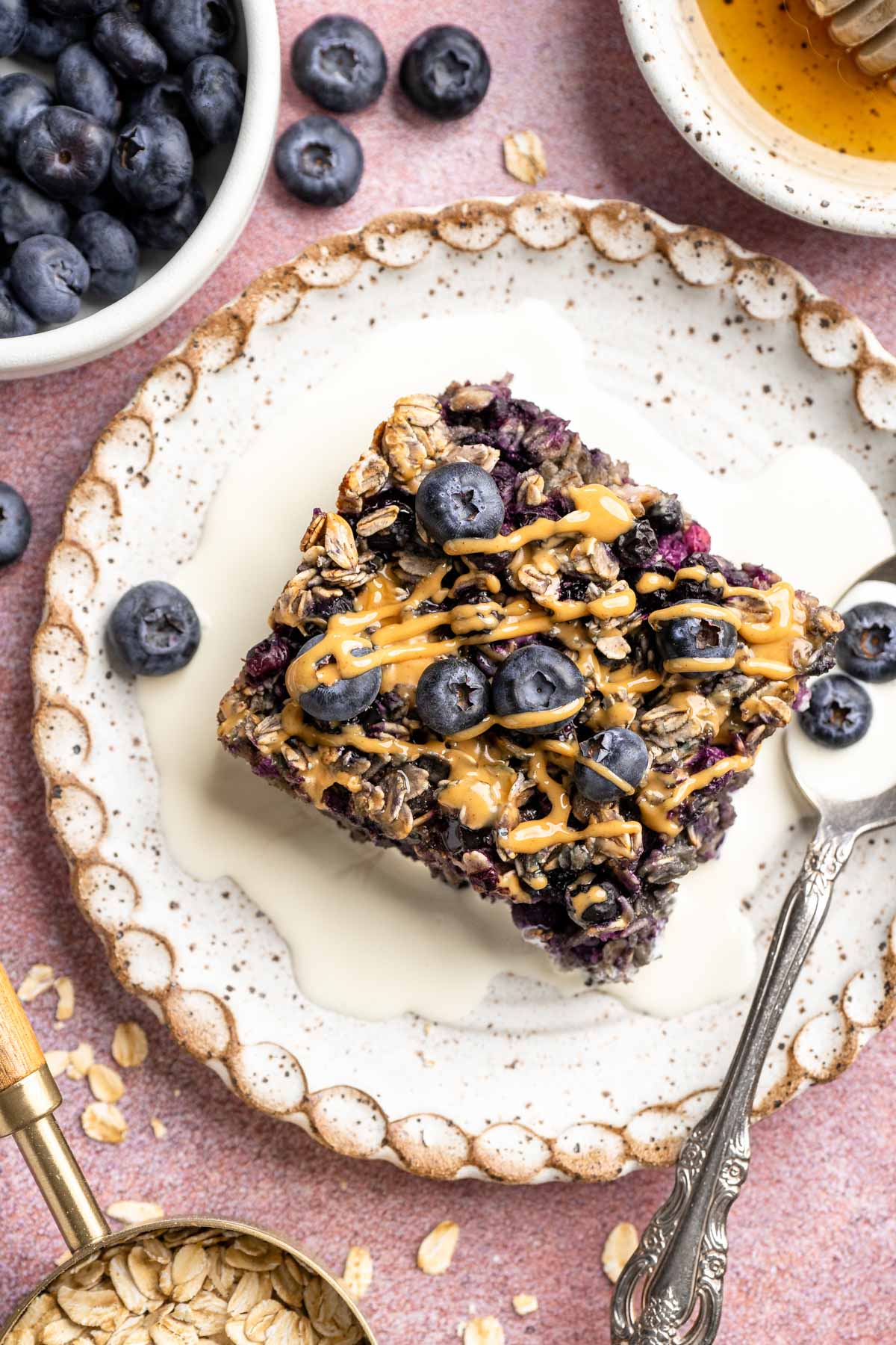Serving of blueberry baked oatmeal on a white plate with a splash of milk.