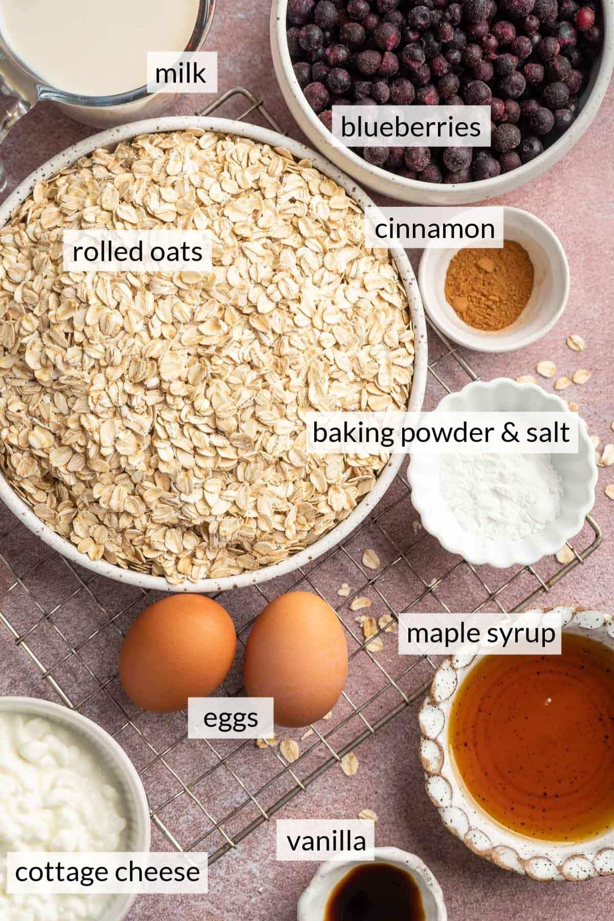 Bowls with rolled oats, frozen blueberries, maple syrup and cottage cheese near two eggs.