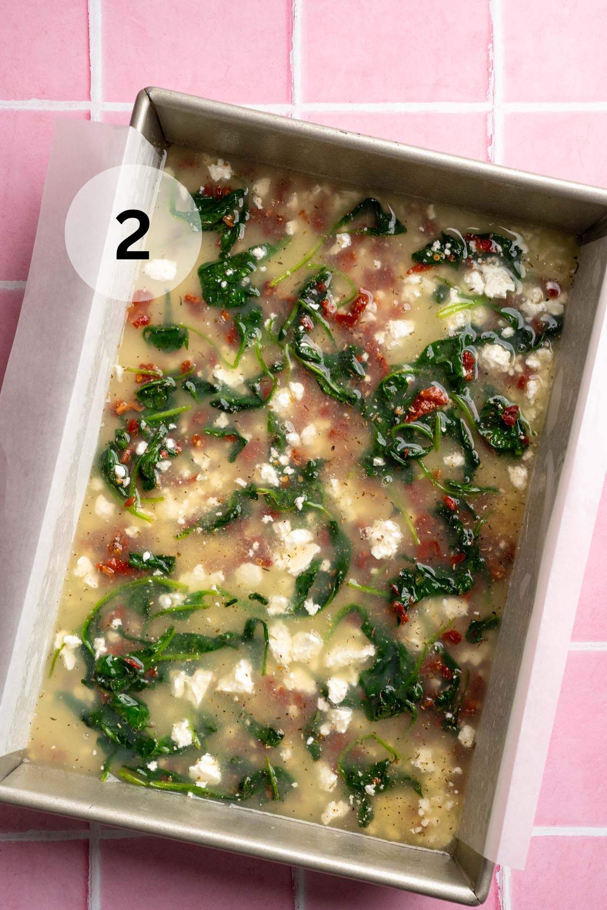 Egg whites poured into a pan with spinach, feta and sun-dried tomatoes.