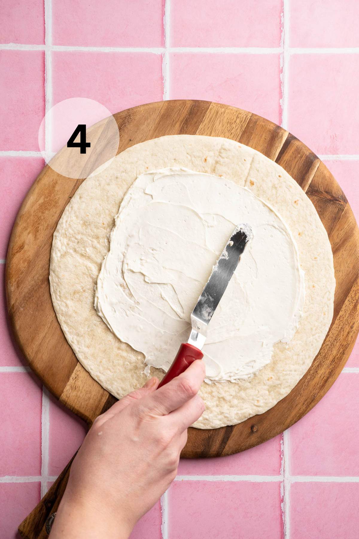 Spreading cream cheese over a tortilla.