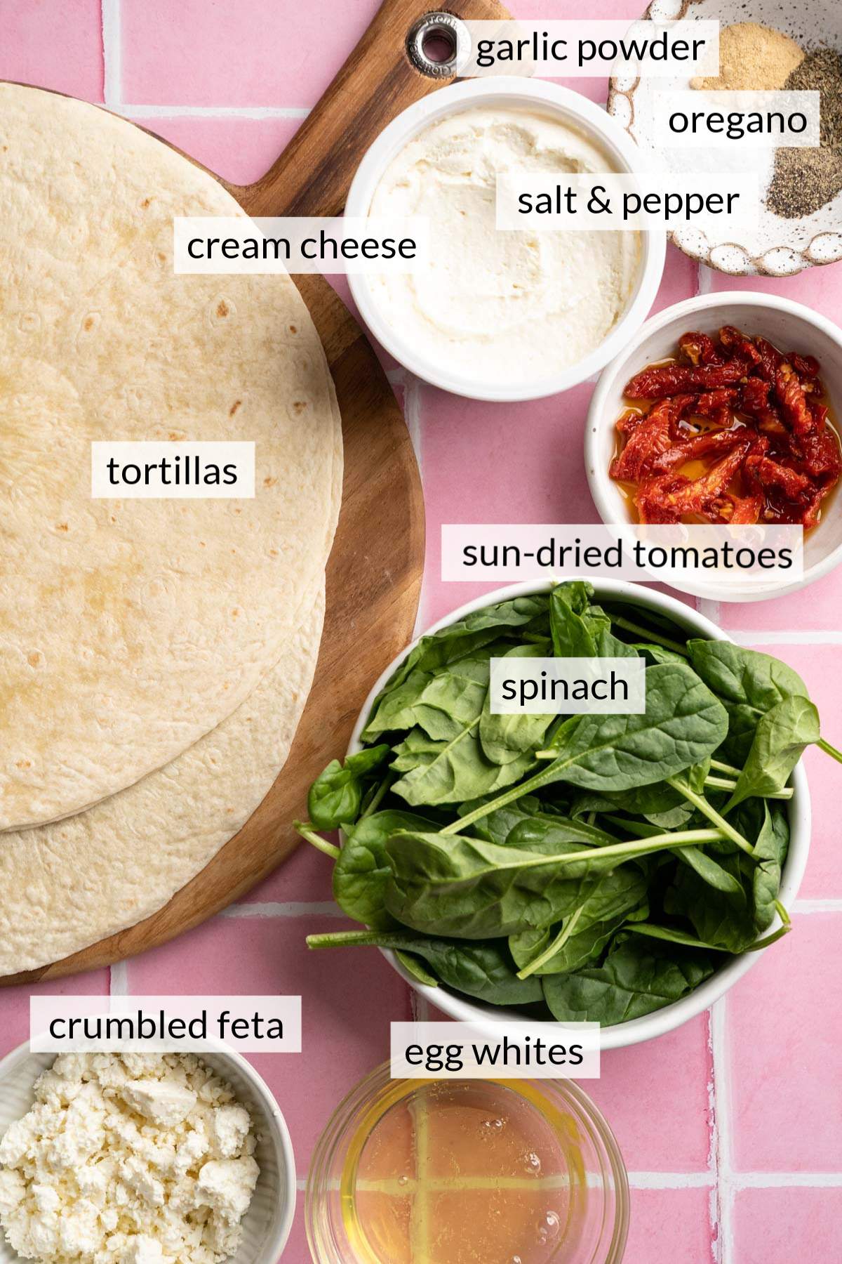 Tortillas, fresh spinach near bowls of crumbled feta, egg whites, sun-dried tomatoes and seasonings.