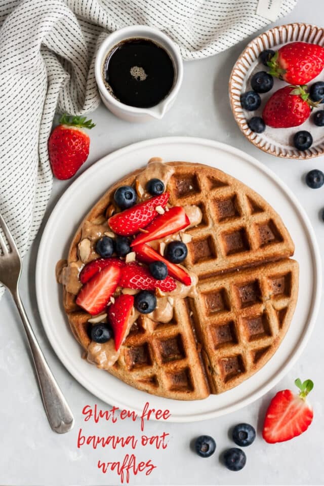 large waffle on a white plate served with berries and syrup