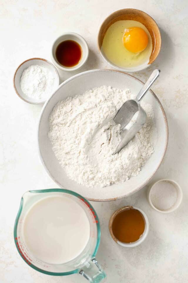 Flour, milk, and an egg divided into portions for making pancakes.