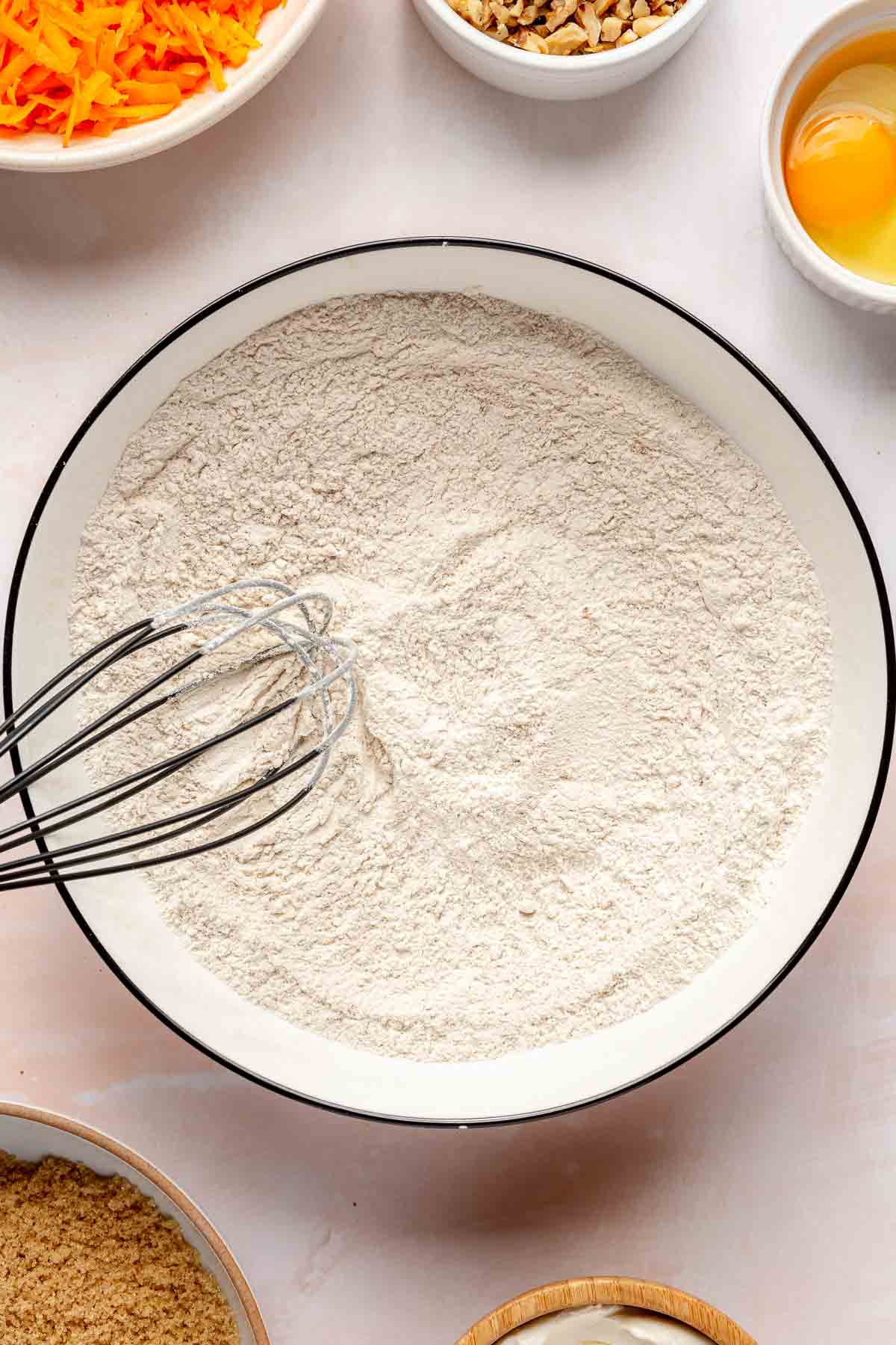 Using a whisk to mix flour with baking powder and baking soda.