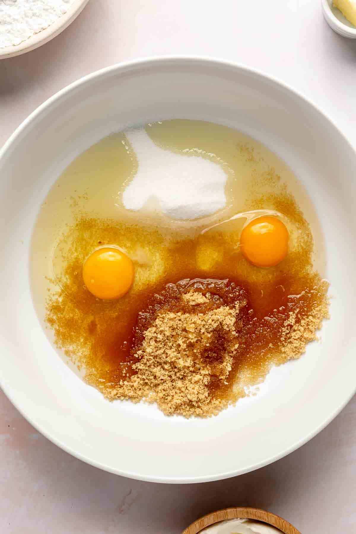 Adding eggs with sugar in a large bowl.