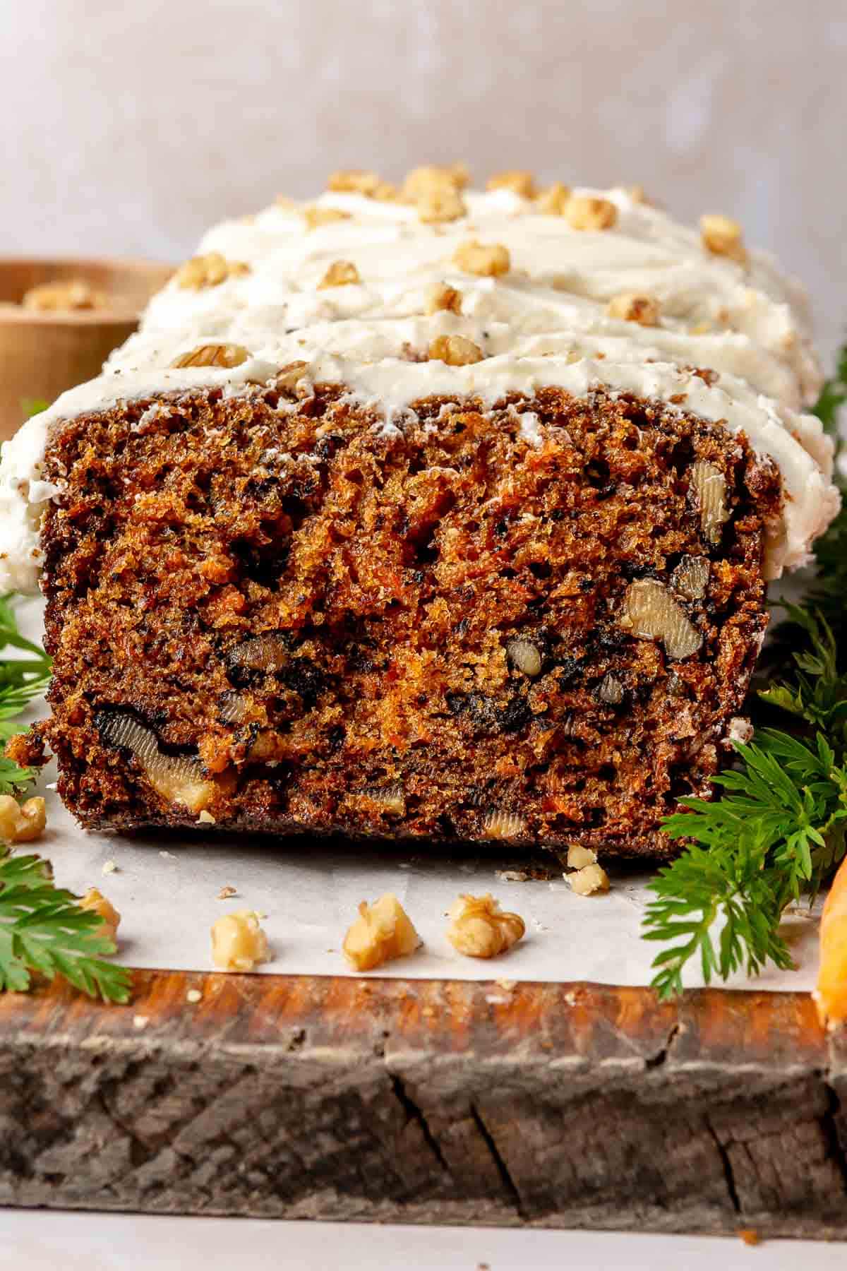 Iced carrot cake loaf topped with chopped walnuts.