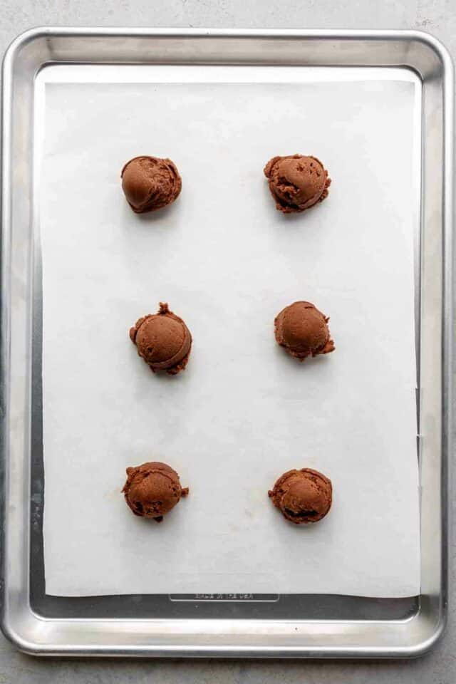 Cookie dough balls on a sheet pan.