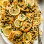 Chicken piccata served over butter noodles with lemon slices.