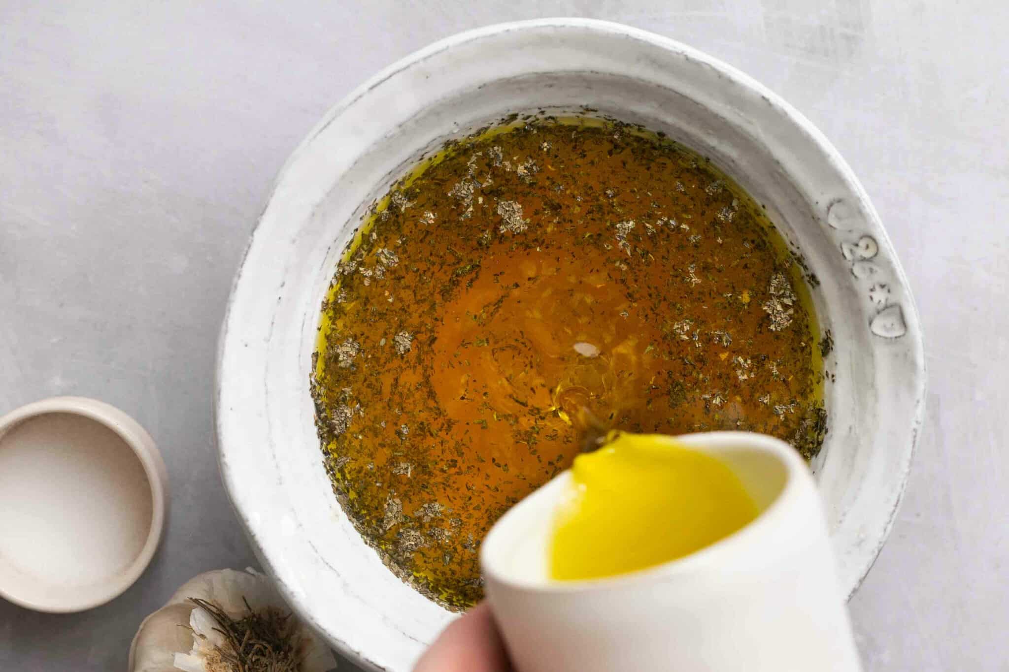 Pouring oil in with other ingredients to make dressing.