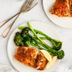 baked cod and broccoli on a white plate served with lemon slices