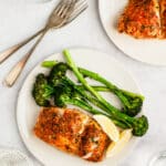 baked cod and broccoli on a white plate served with lemon slices