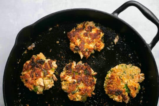 Cooking salmon croquettes in a skillet.