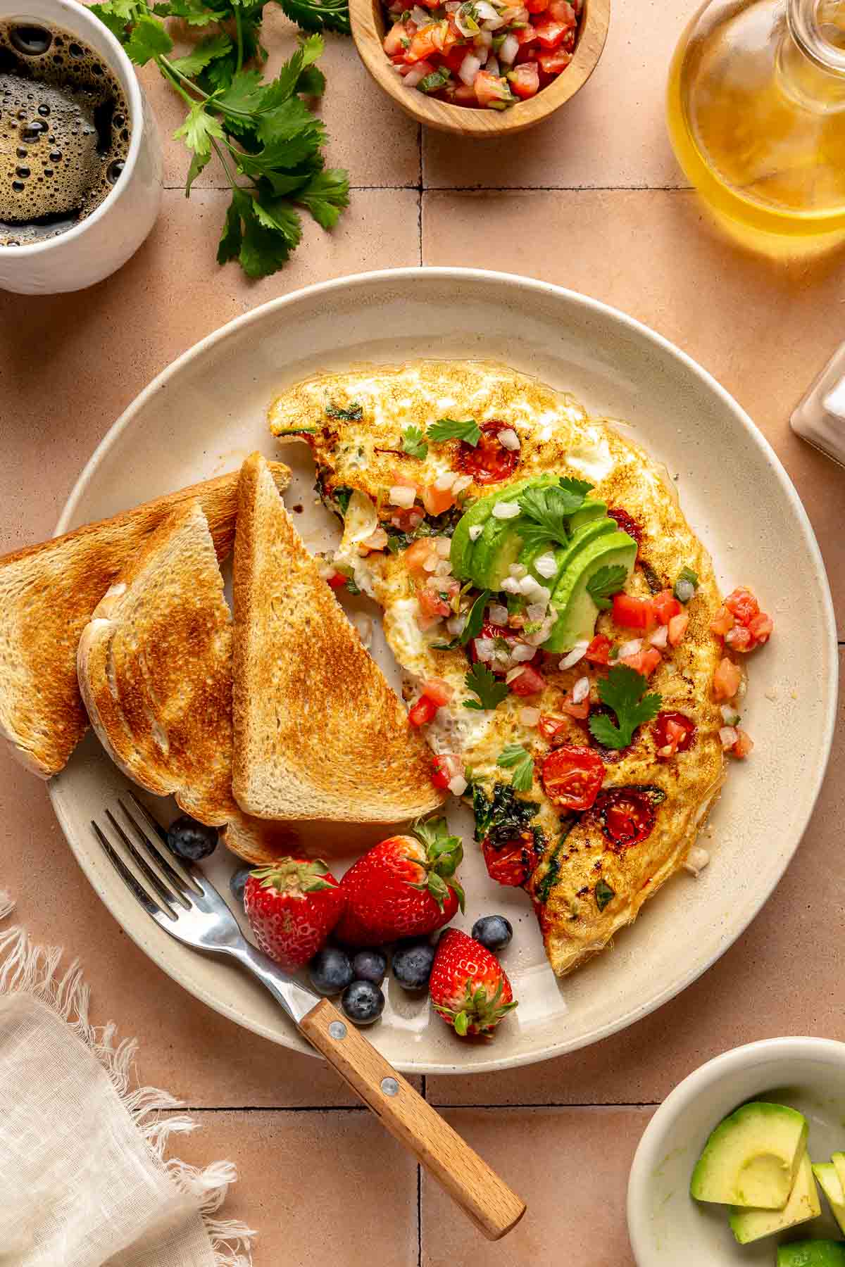 Omelet topped with avocado and cilantro.