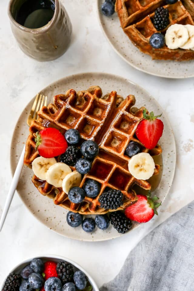 protein waffles drizzled with syrup and topped with fresh fruit