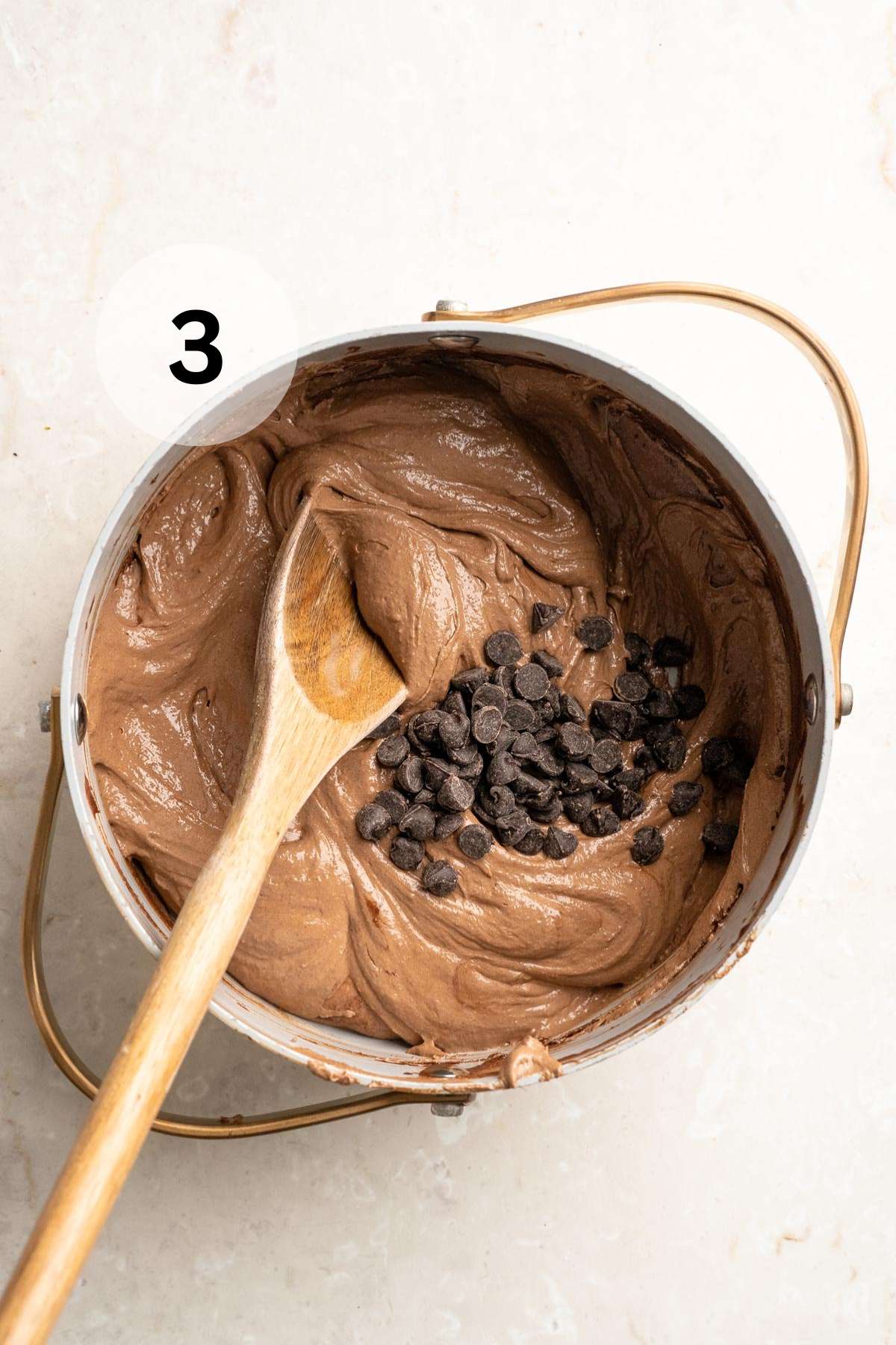 Stirring chocolate chips into brownie batter in a pot.