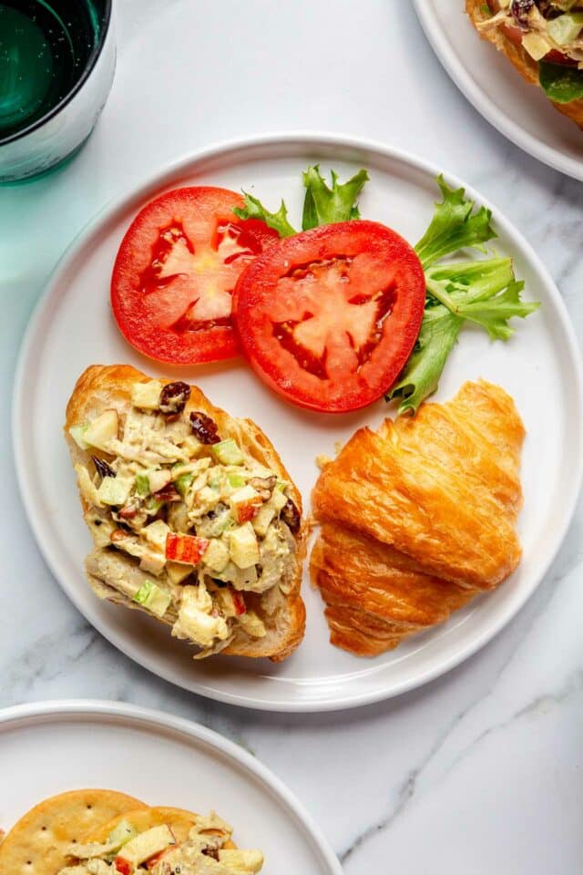 Curried chicken served on croissant with sliced tomato.