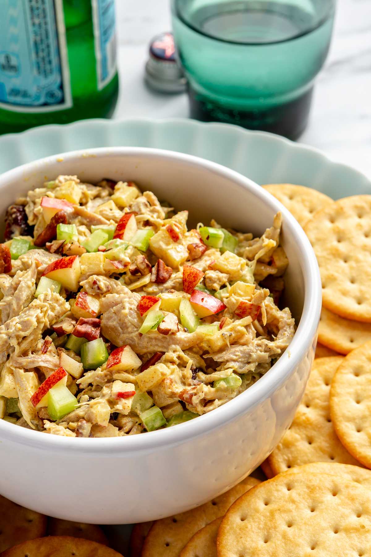 Curried chicken salad in white bowl served with crackers.