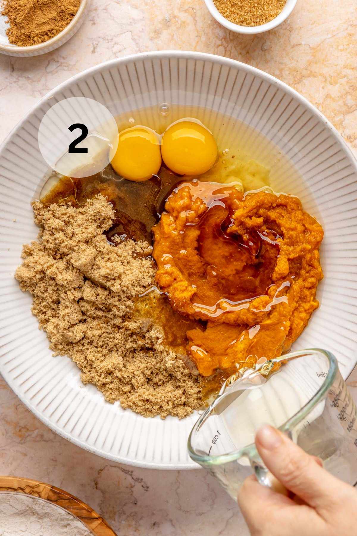 Combining eggs, pumpkin, sugar and oil in a white bowl.