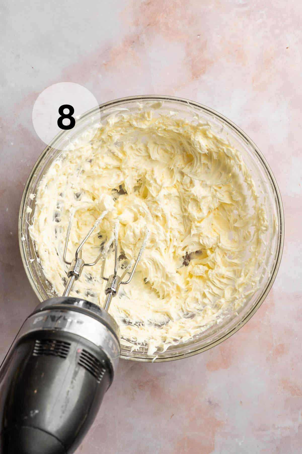 Beating butter with a handheld mixer.