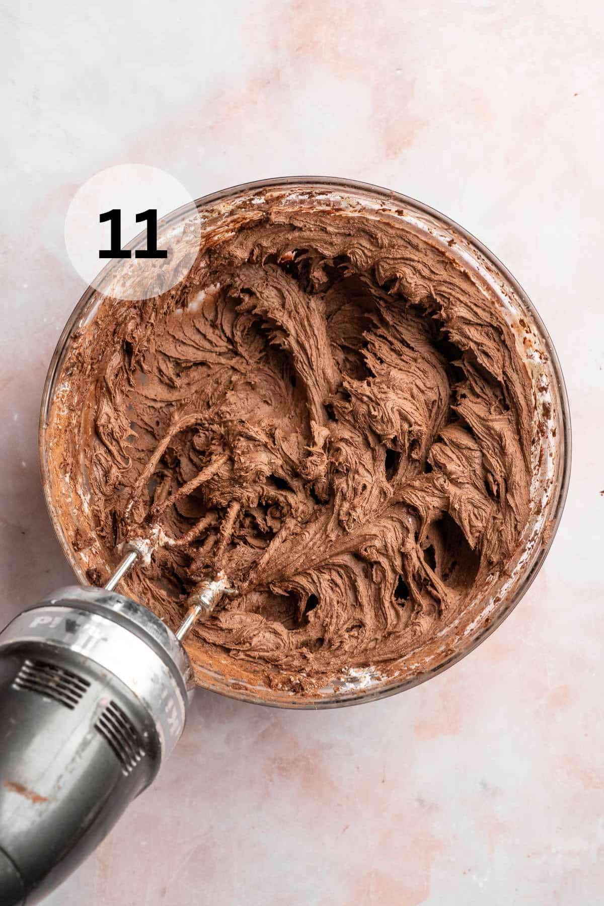 Mixing chocolate buttercream frosting in a large bowl.