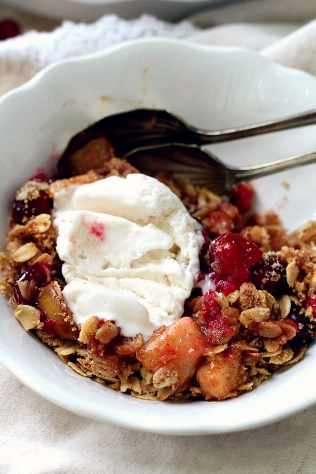 Healthy Cranberry Pear Crisp served in a white bowl with vanilla ice cream