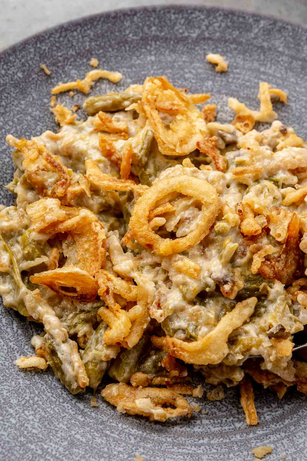 A serving of green bean casserole served on a gray plate.