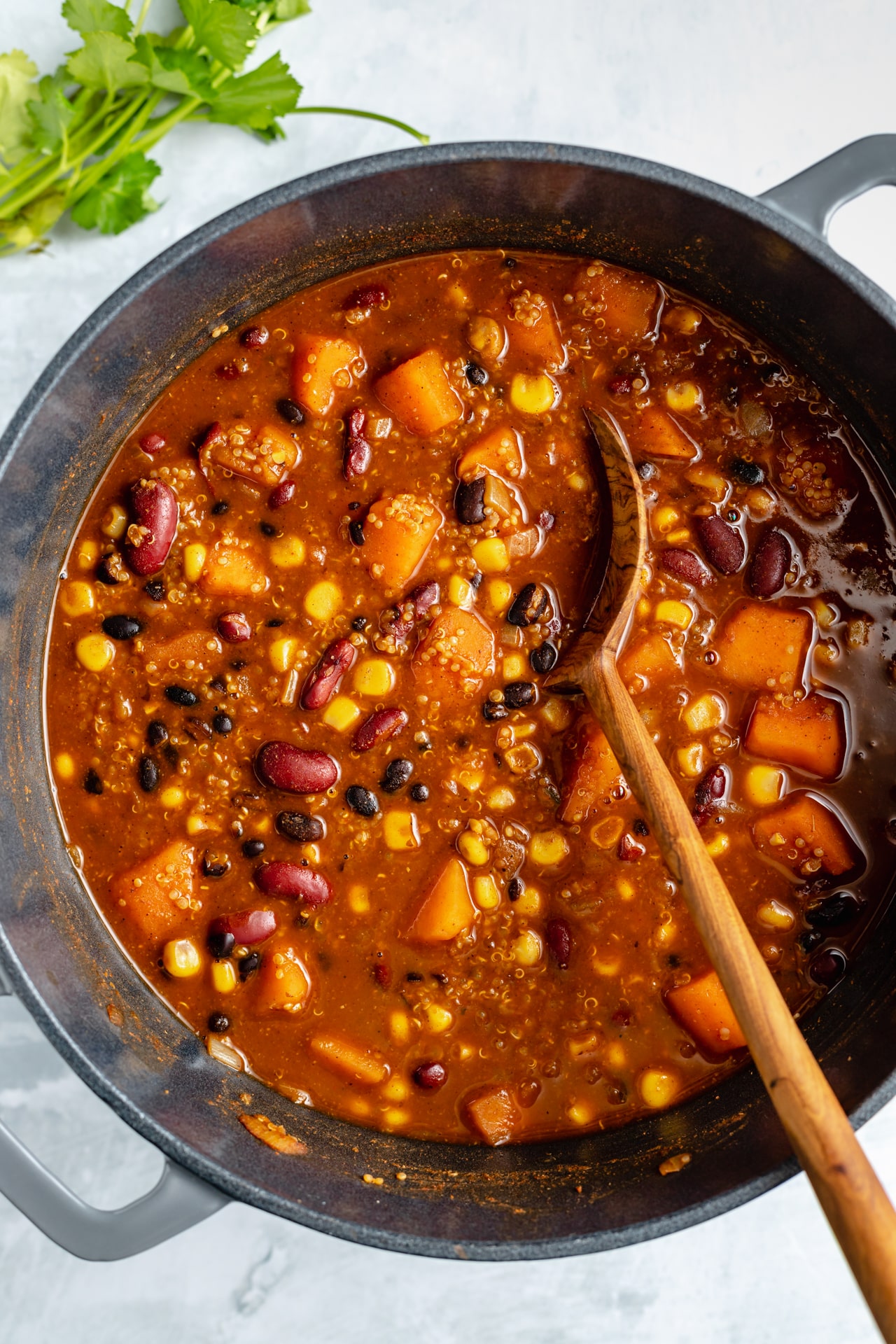 stirring quinoa bean chili with a wooden spoon