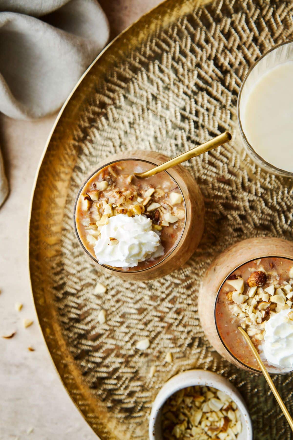 Overhead view of overnight oatmeal topped with nuts and whipped cream.
