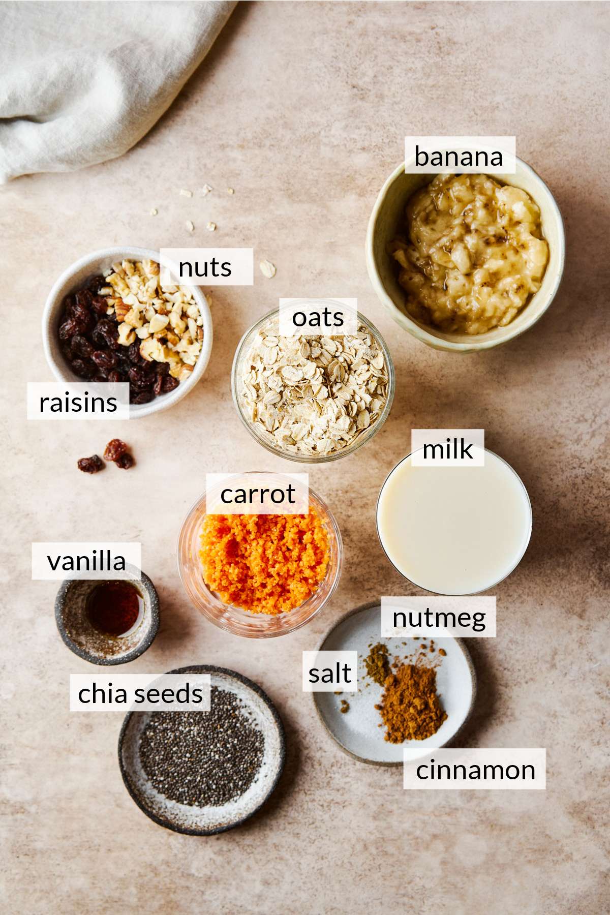 Small bowls with oats, grated carrot, milk, spices, chia seeds and mashed banana.