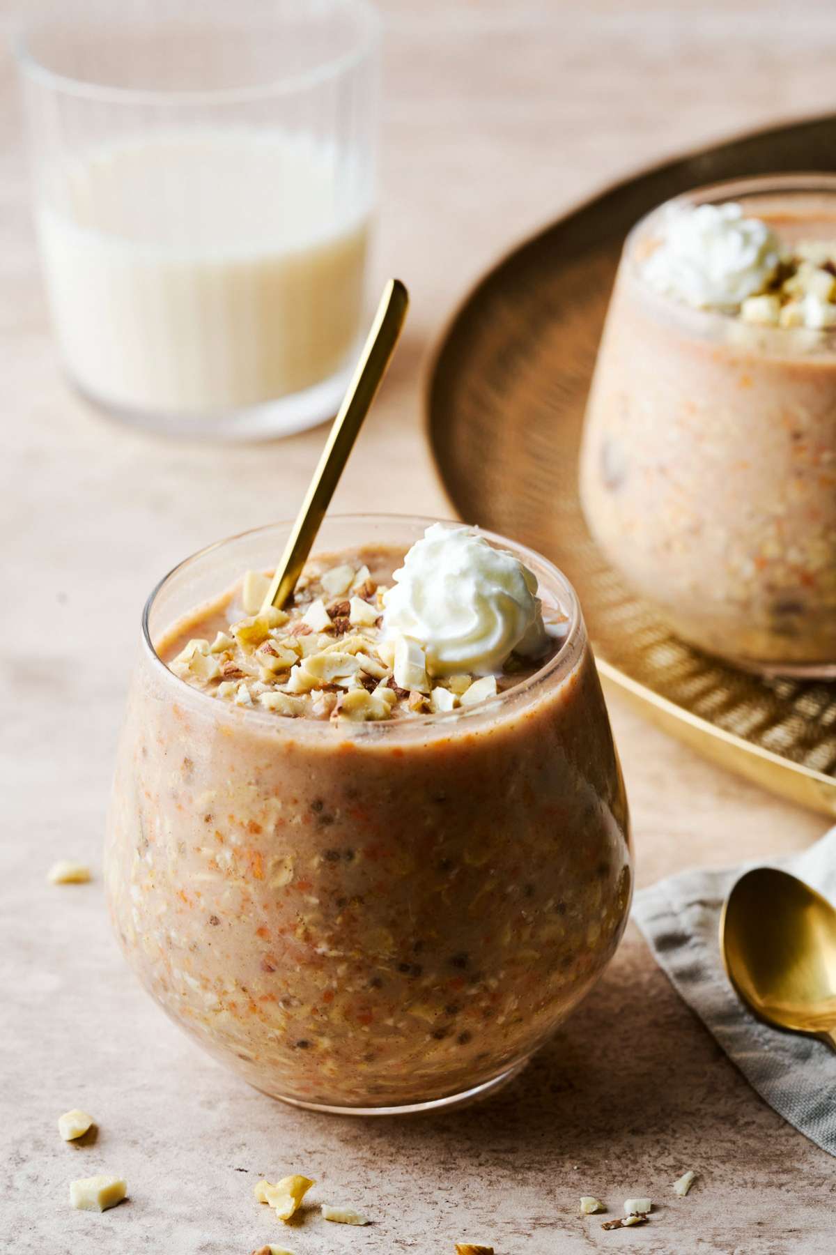 Carrot cake overnight oats topped with whipped cream near a glass of milk.