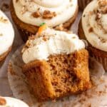 Carrot cake cupcakes with a bite taken out of one.