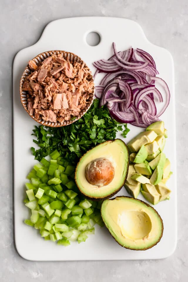 ingredients for avocado tuna salad on a white cutting board