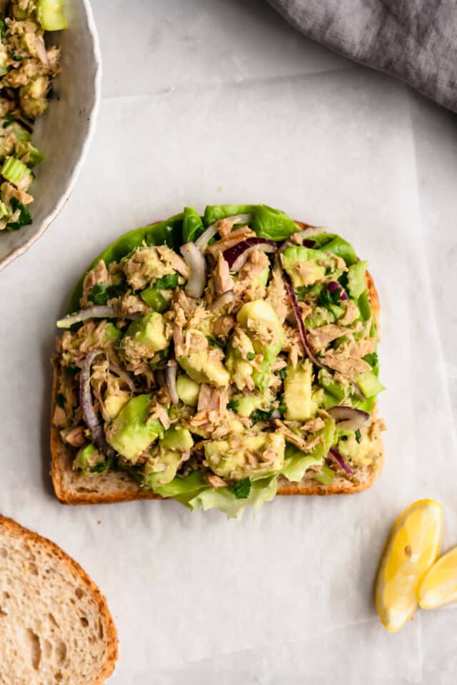 one slice of sandwich bread topped with avocado tuna salad