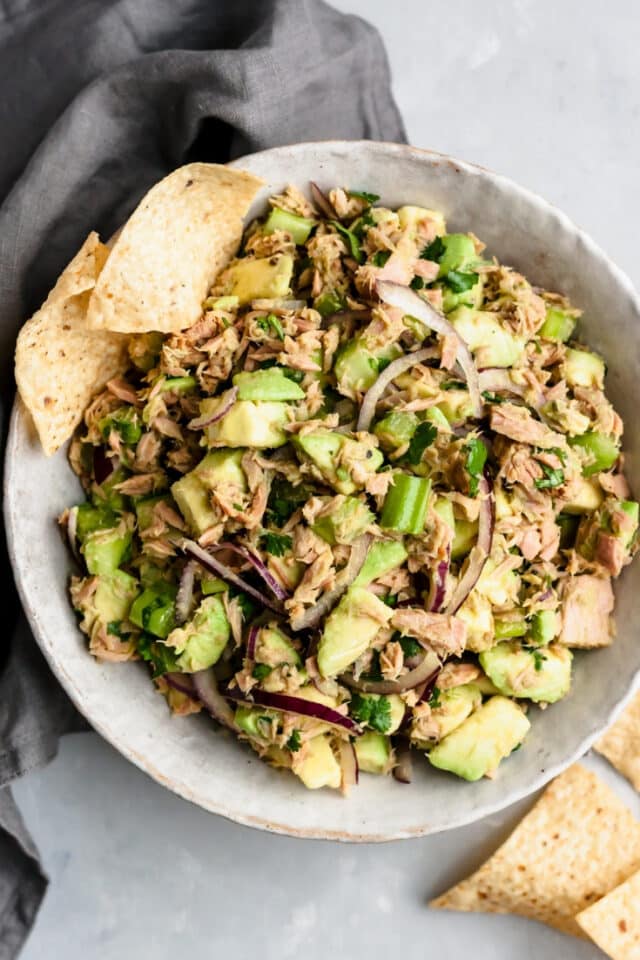 Easy Avocado Tuna Salad in a large white serving bowl with a few tortilla chips on the side