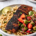Blackened salmon on a plate with strawberry avocado salsa and rice.
