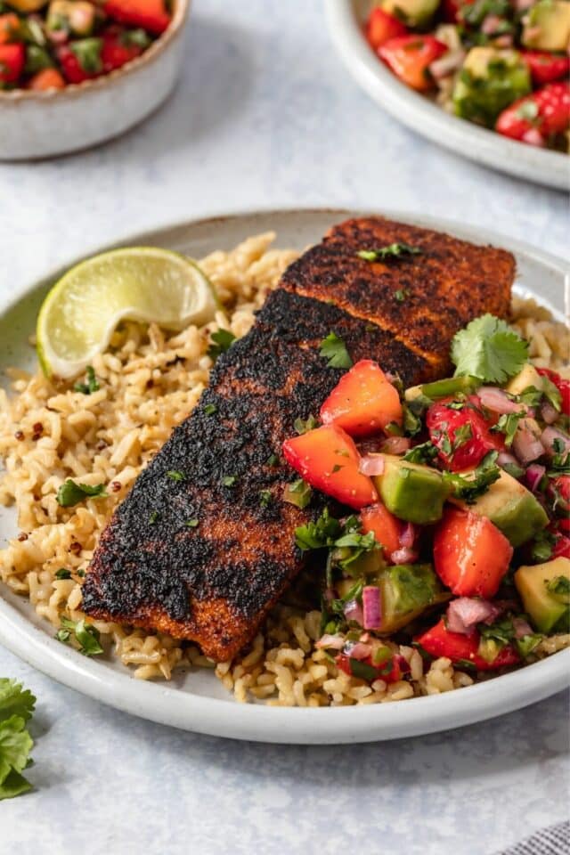blackened salmon served on a plate with rice and a lime wedge