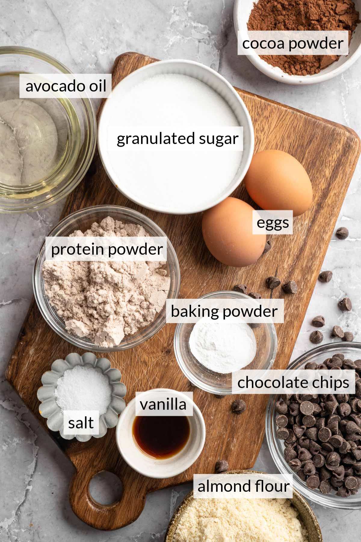 Small bowls with sugar, protein powder, almond flour, vanilla and chocolate chips.