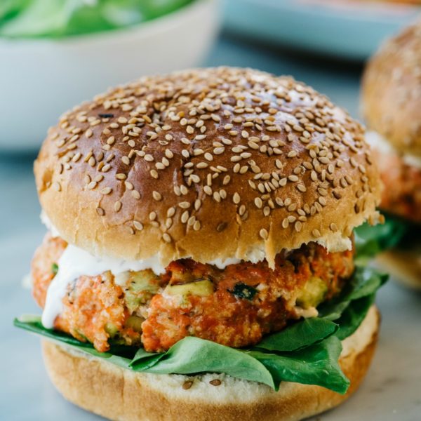 Salmon burger on a sesame seed bun with ranch and spinach