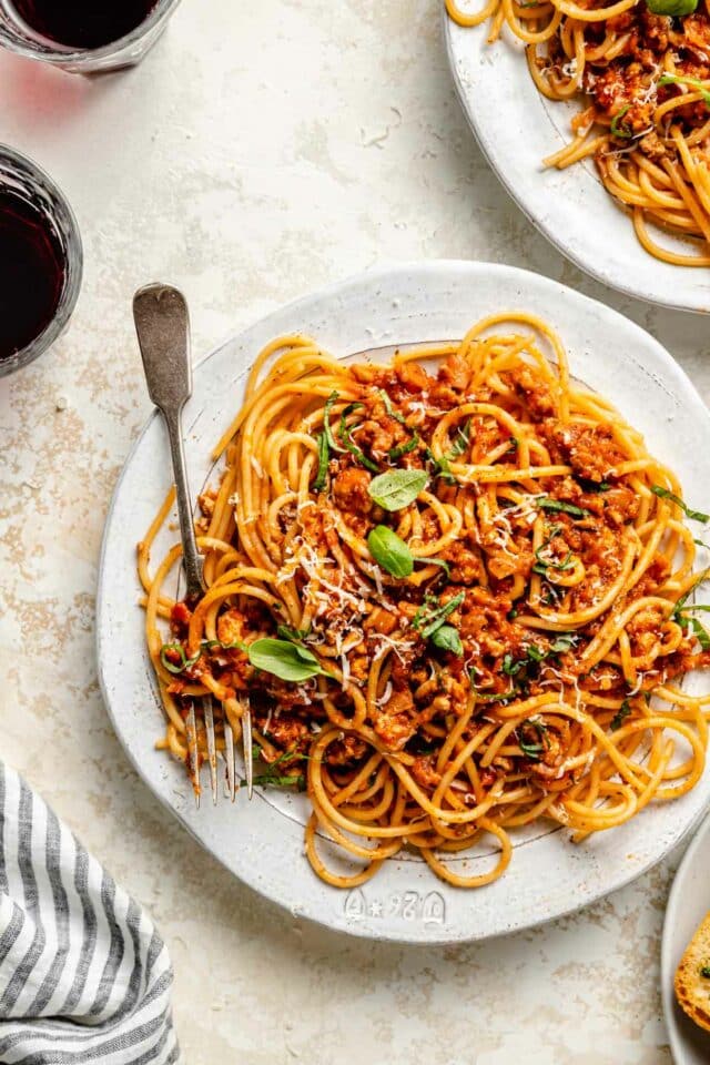 Spaghetti with meat sauce on a plate served with red wine.