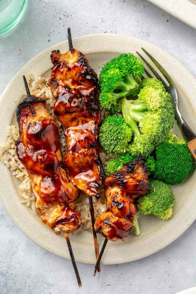 Chicken skewers served over brown rice with broccoli.