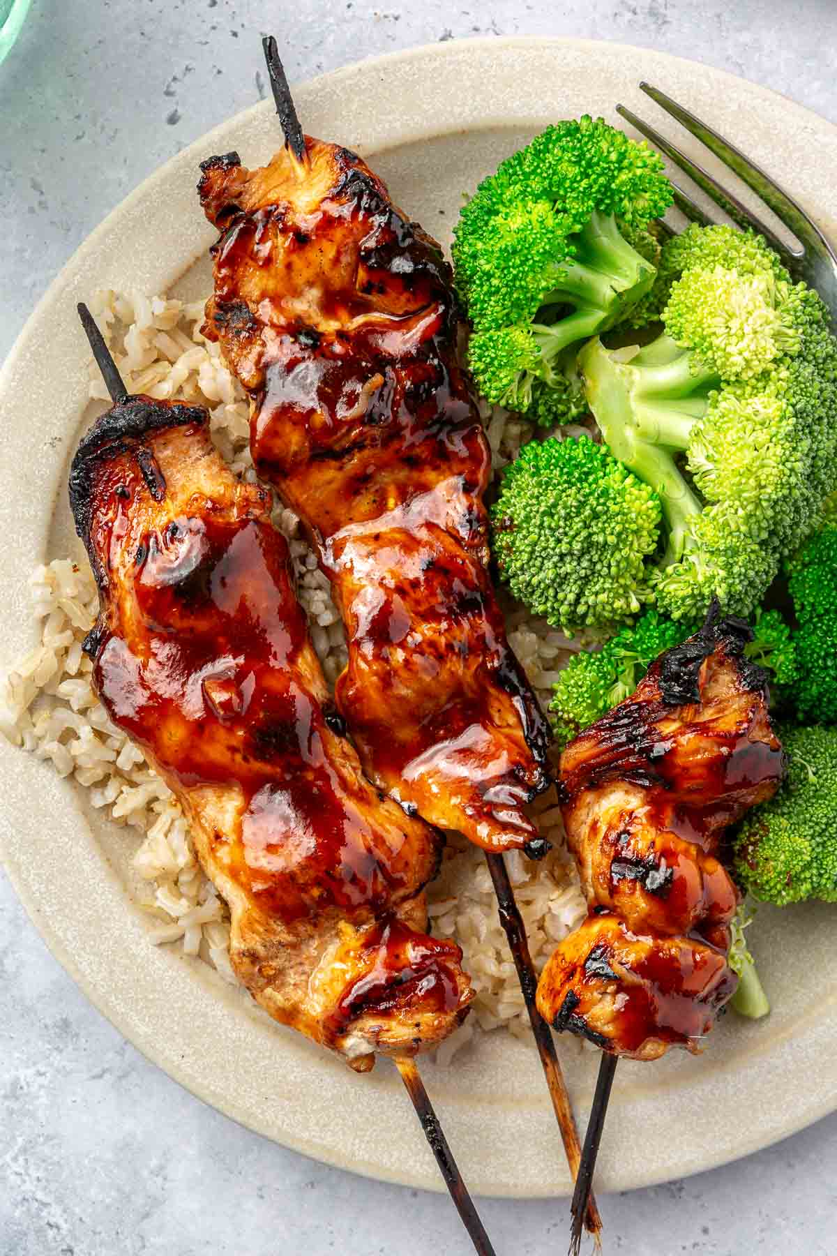 Grilled chicken on wooden kabobs served with rice and broccoli.