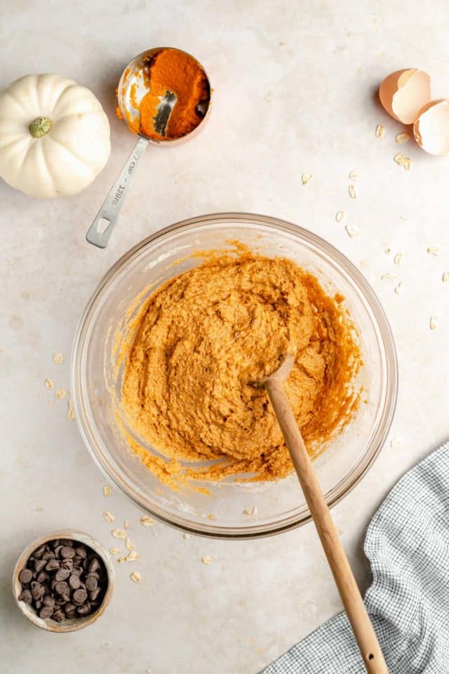 stirring pumpkin puree with oat flour in a large mixing bowl