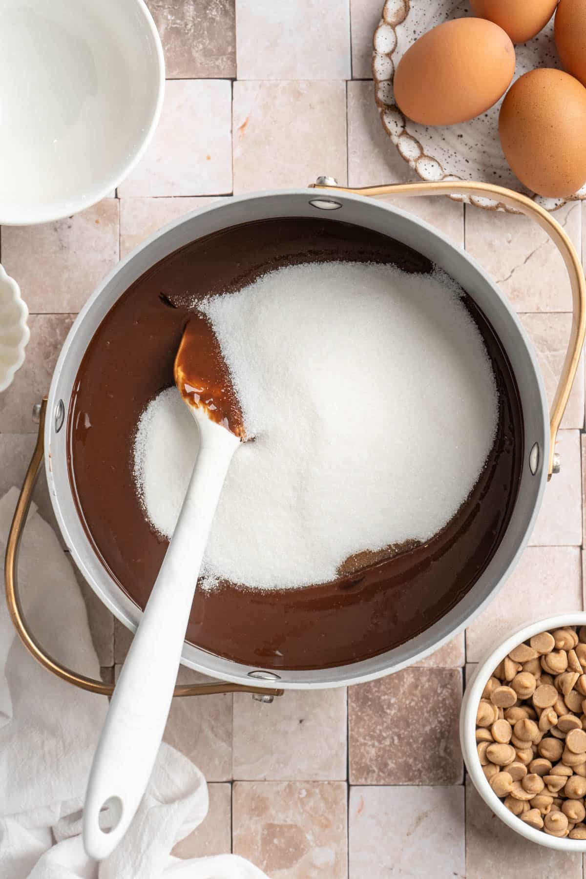 Stirring sugar into chocolate mixture in a pot.