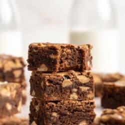 Three peanut butter brownies stacked and the top one has a bite taken out.